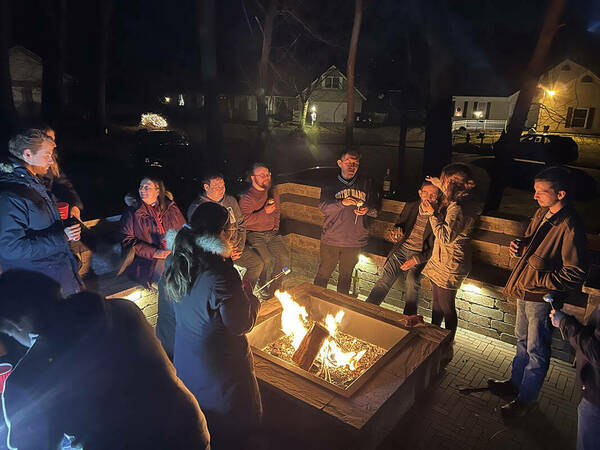 A picture of lab members cozy around the bonfire in our Winter party 2021.